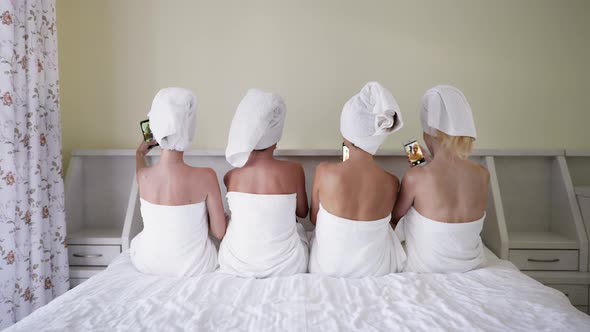 Girlfriends in Towels Make Selfie on Smartphones While Lying on Bed alt