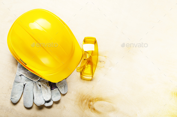 Flat lay view at yellow plastic hard hat glasses and protective gloves