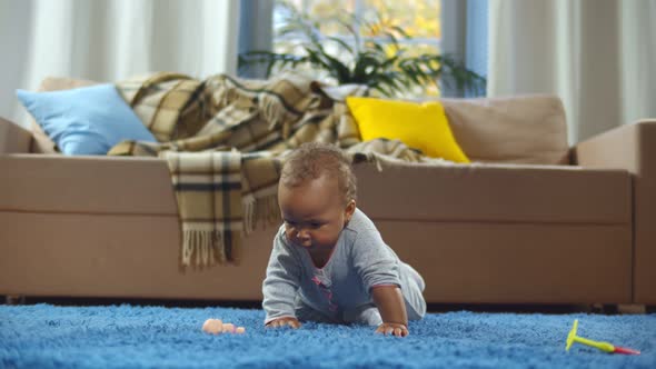 Cute Adorable African Infant Child Playing with Toys on Blue Carpet at Home alt