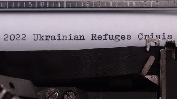 Typing phrase "2022 Ukrainian Refugee Crisis" on retro typewriter. alt
