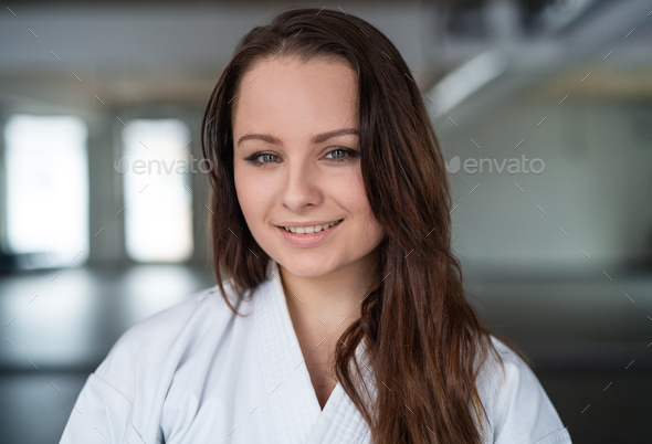 A portrait of young karate woman standing indoors in gym.