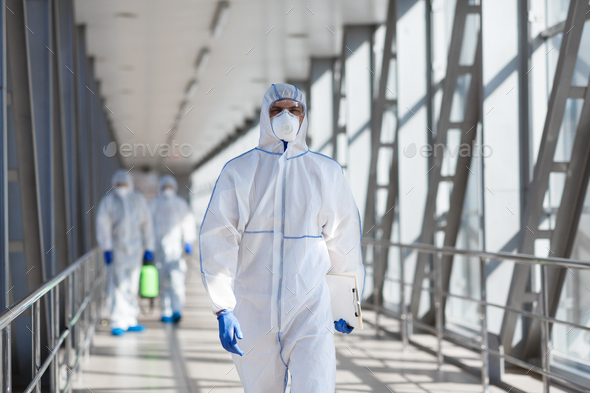Disinfectant workers in protective mask and suit sprays bacterial or virus