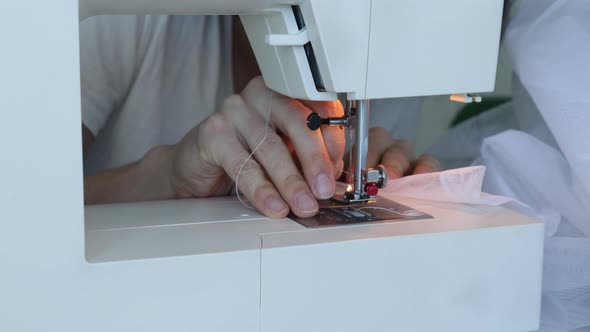 Process of inserting thread into needle of industrial white sewing machine.