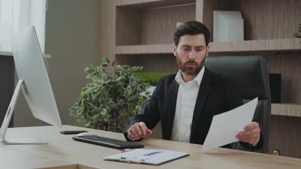 Handsome Professional Works in His Office with Some Data and Charts Looking Concentrated and Busy alt