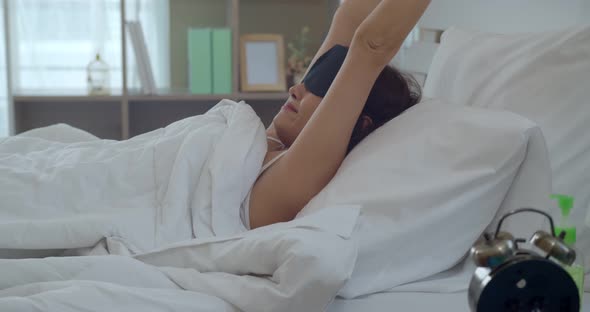 Asian young woman waking and touching alarm clock