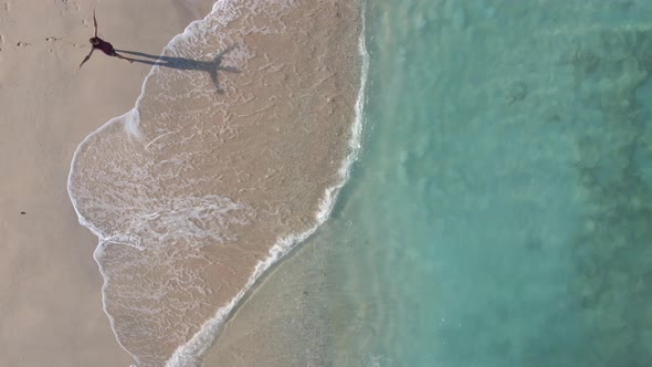 Man with raising arms walking into the clear sea during sunny day on peaceful Gili Island,Asia. alt