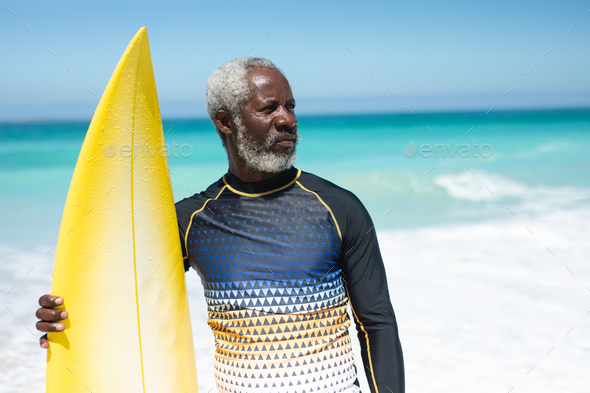 Old man with a surfboard at the beach