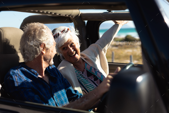 Old couple with a car at the beach