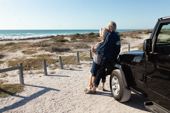 Old couple with a car at the beach