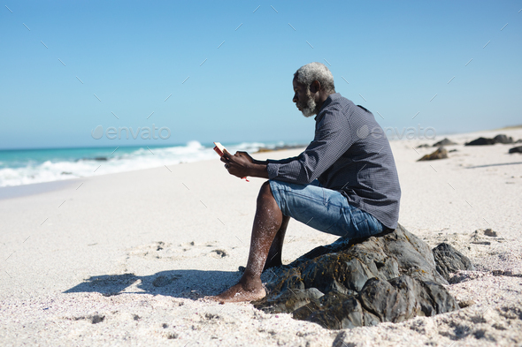 Old man reading book at the beach