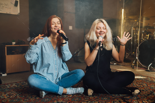 Two young woman sitting singing a duet - Stock Photo - Images