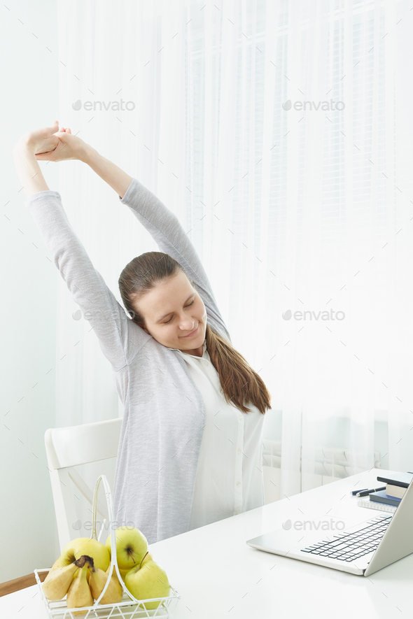 Woman stretches her arms, kneads her back from fatigue. Long sitting at computer, muscle cramps.