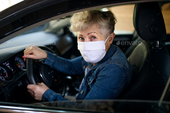 Senior woman driver with face mask in car, quarantine concept