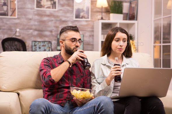 Couple watching a movie sitting comfortable on couch