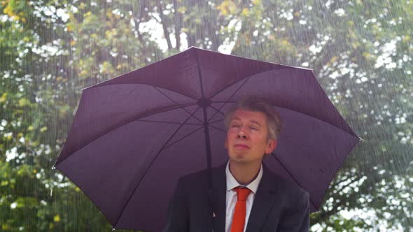 Businessman Sheltering Underneath an Umbrella in the Rain