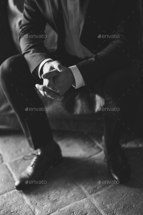 man sitting with hands on the knees and fingers locked