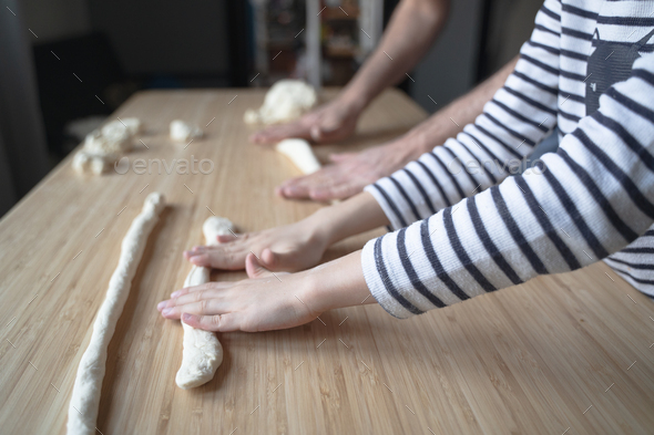 little Caucasian child working the dough with his father on a wood cutting board - Stock Photo - Images