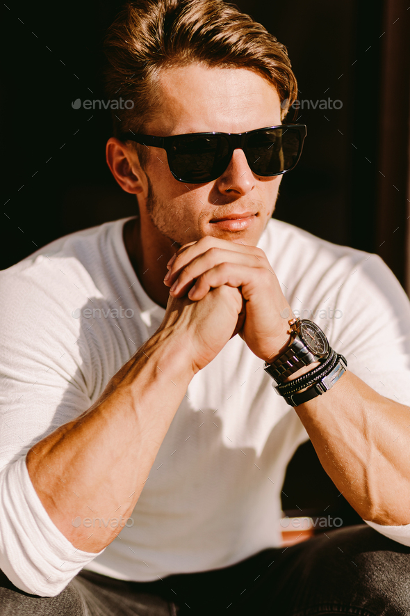 portrait of a brutal man in sunglasses and watch outdoors