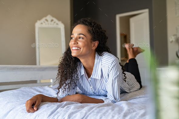 Happy young mixed race woman relaxing on bed - Stock Photo - Images
