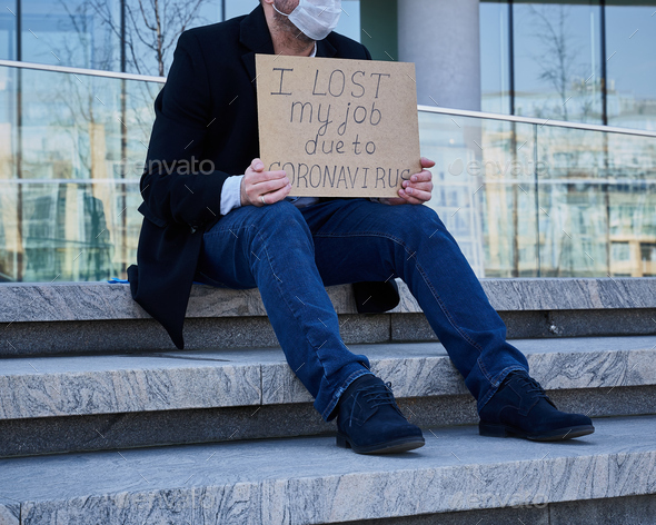 Job loss due to COVID-19 virus pandemic concept. Unrecognizable man holds sign 