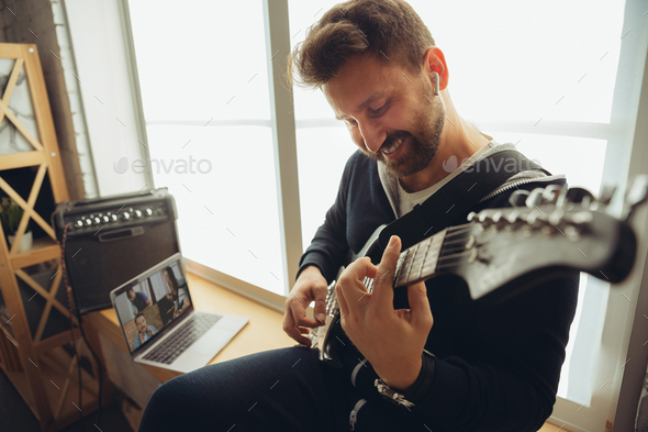 Caucasian musician playing guitar during concert at home isolated and quarantined, cheerful