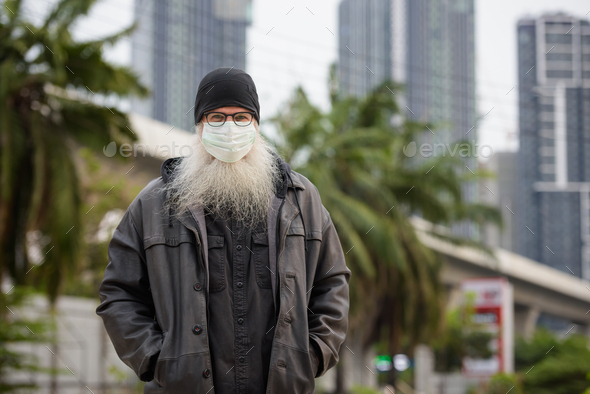 Mature bearded hipster man with mask for protection from corona virus outbreak