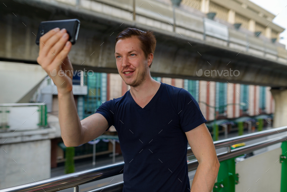 Happy young handsome man taking selfie at sky train station