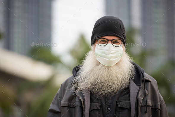 Face of mature bearded hipster man with mask for protection from corona virus outbreak