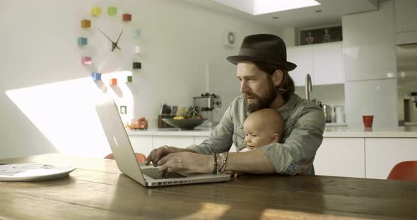 Father working on laptop with daughter in kitchen