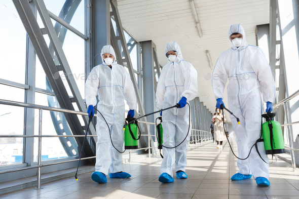 Medical staff wearing protective clothing disinfects the public place