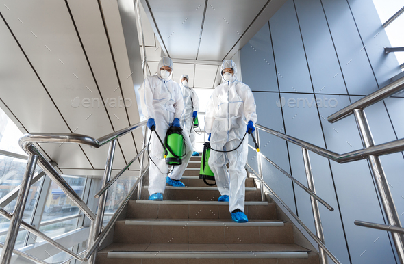 Government workers in protective suits making disinfection of stairs