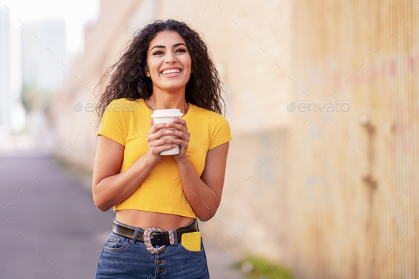 Arab girl walking across the street with a take-away coffee