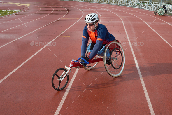 Handicapped sportsman in helmet and sunglasses sitting in racing wheelchair