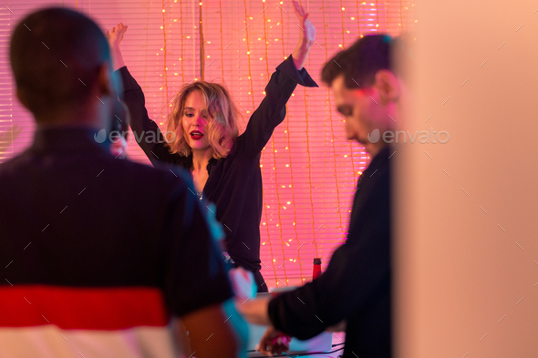 Young ecstatic blonde female in black shirt raising hands while dancing