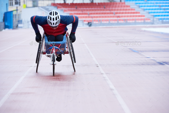 Handicapped sportsman in helmet covering distance in three-wheeled chair