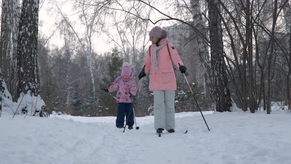 Little Girl with Mom Cross Country Skiing in Park alt