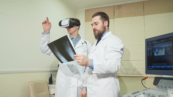 Doctor Using 3d Vr Glasses While His Colleague Examining X-ray of a Patient alt