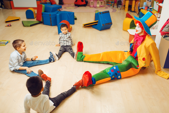 Funny clown play with boys in kindergarten