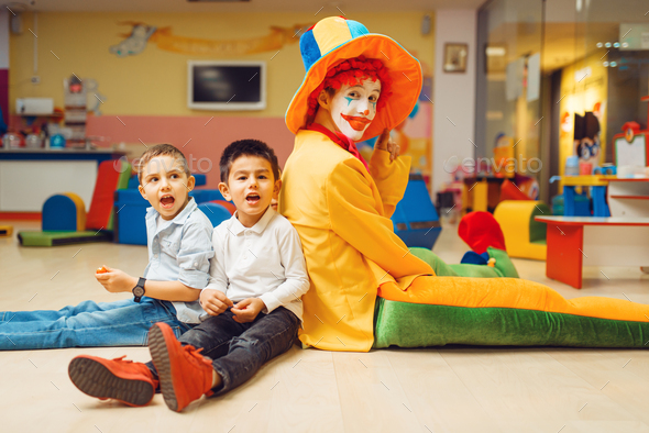 Funny clown play with boys in kindergarten