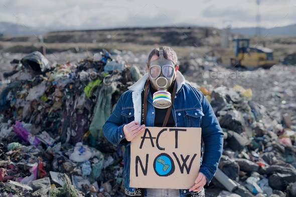 Man with gas mask and placard poster on landfill, environmental concept