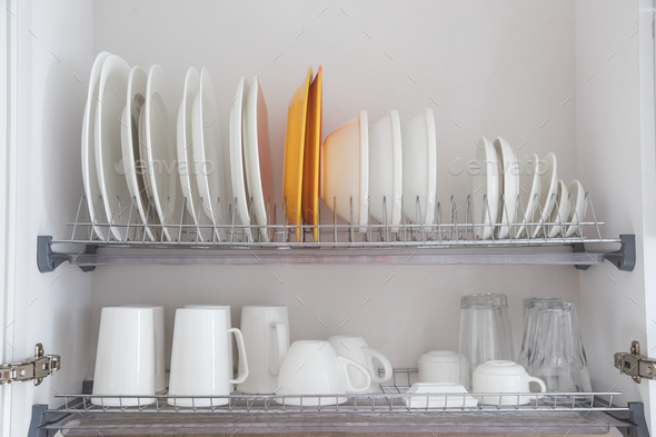 Dish drying metal rack with big nice white clean kitchenware. Traditional  wall cabinet kitchen Stock Photo by Vladdeep