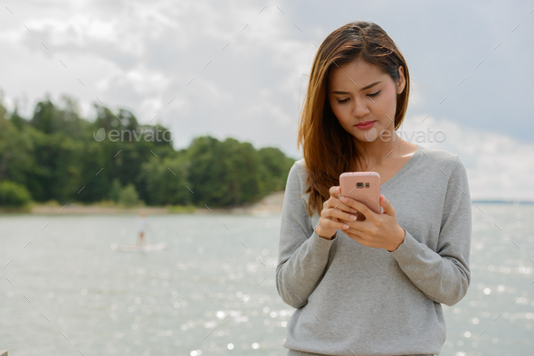 Young beautiful Asian woman against scenic view of the lake