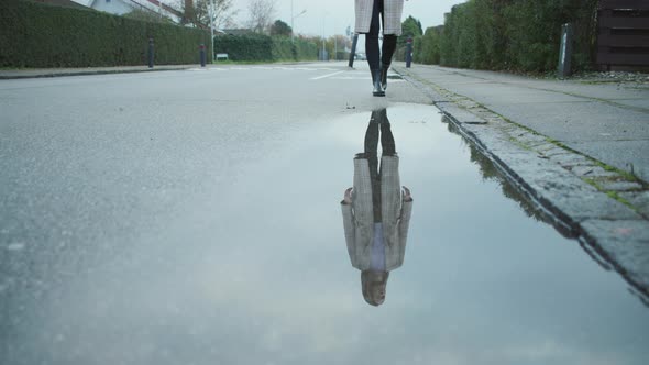 Woman In Boots Reflected In Puddle