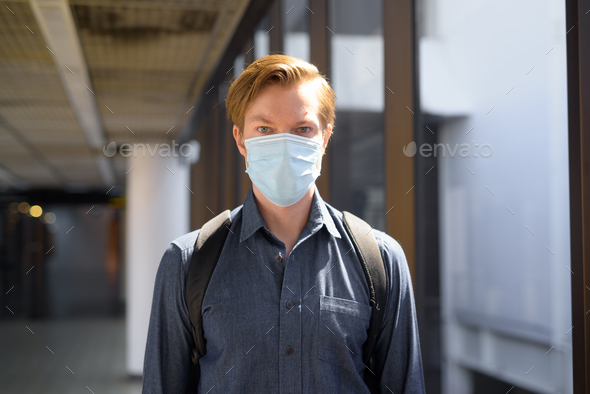 Young tourist man travelling with mask for protection from corona virus outbreak at the airport