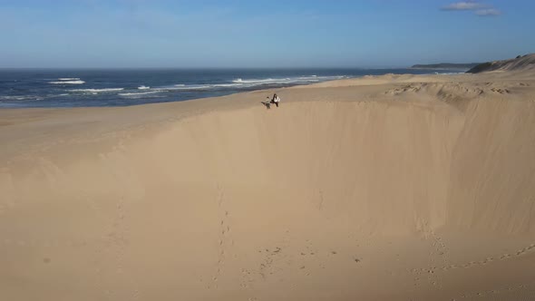 Woman and Her Son Sitting on Edge of Dune