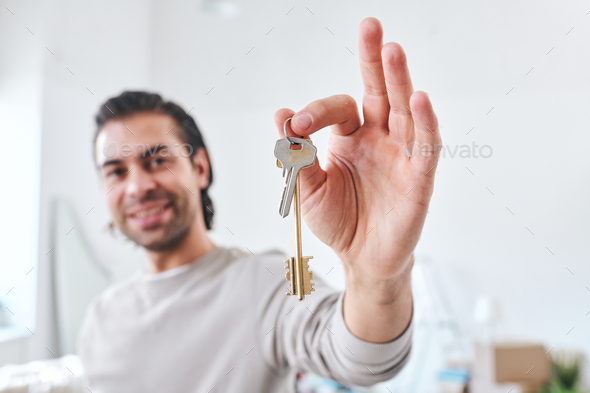 Hand of happy young male settler or buyer of new house showing you the key