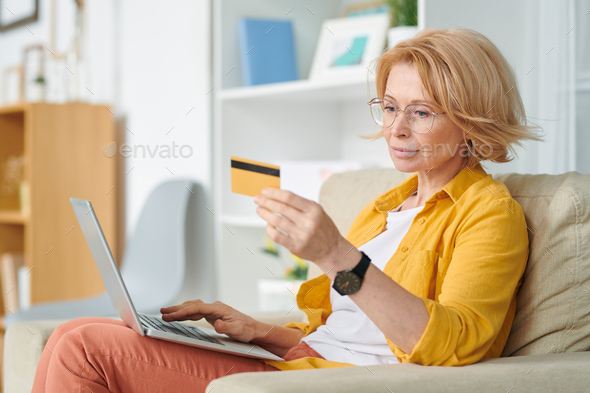 Pretty blond female looking at credit card while going to buy food online