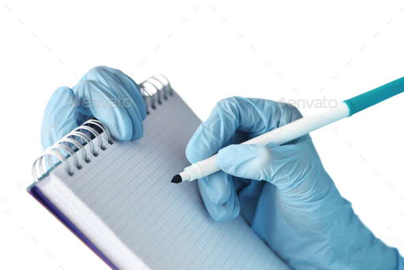 Close up of doctor's hand in gloves with notepad and marker