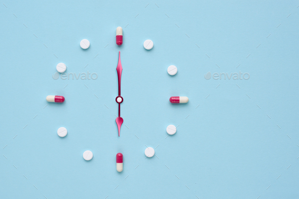 Clock created from pills and capsules on pastel blue background