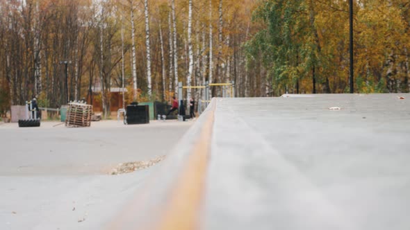 Skater Practicing in the Autumn Concrete Skate Park Making Tricks and Rides in Ramp alt
